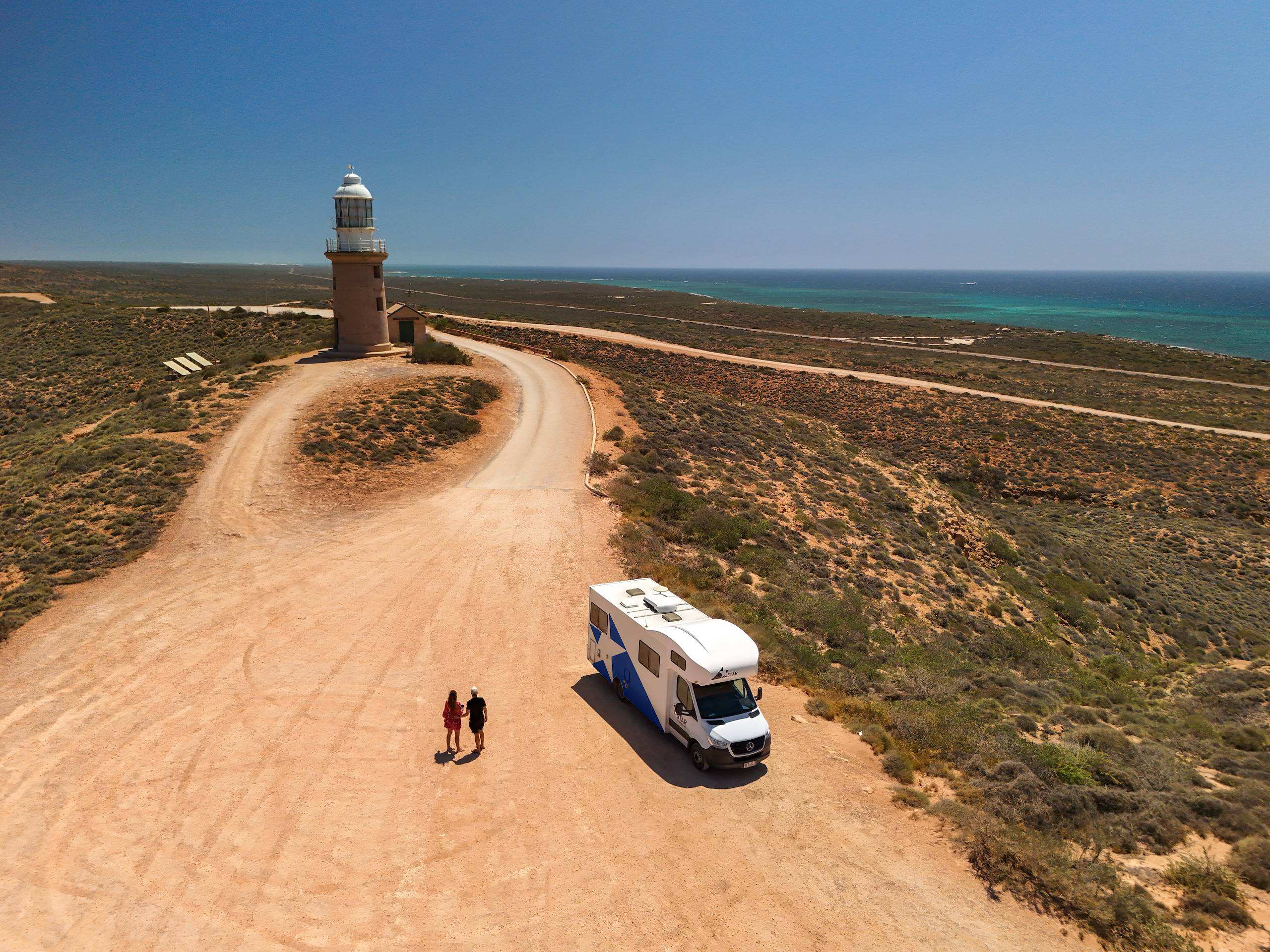 Star RV Polaris 6 parked on dirt road next to Exmouth lighthouse with couple walking toward it