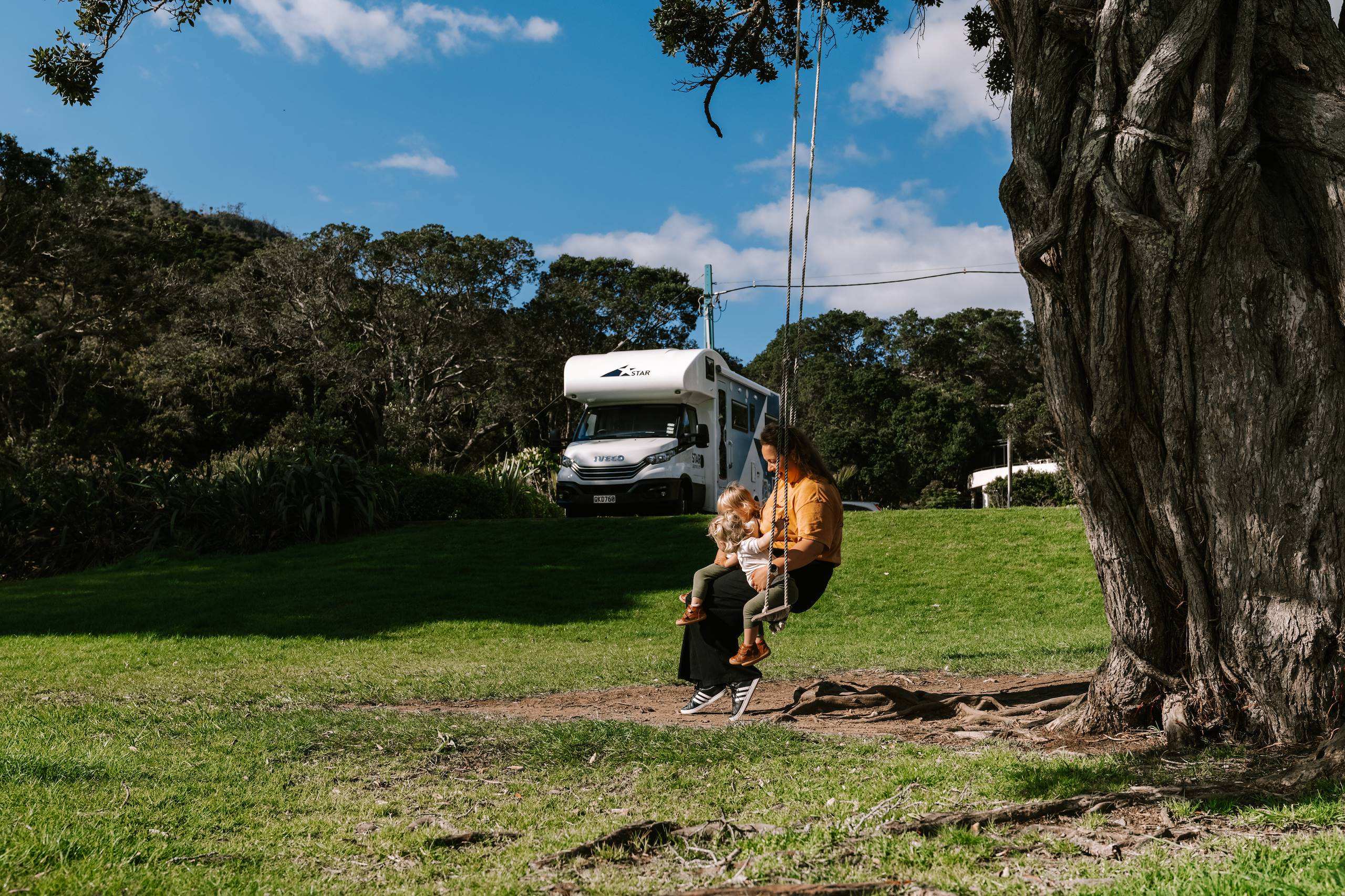 Mother and two twin girls swinging on a rope swing tied to a tree