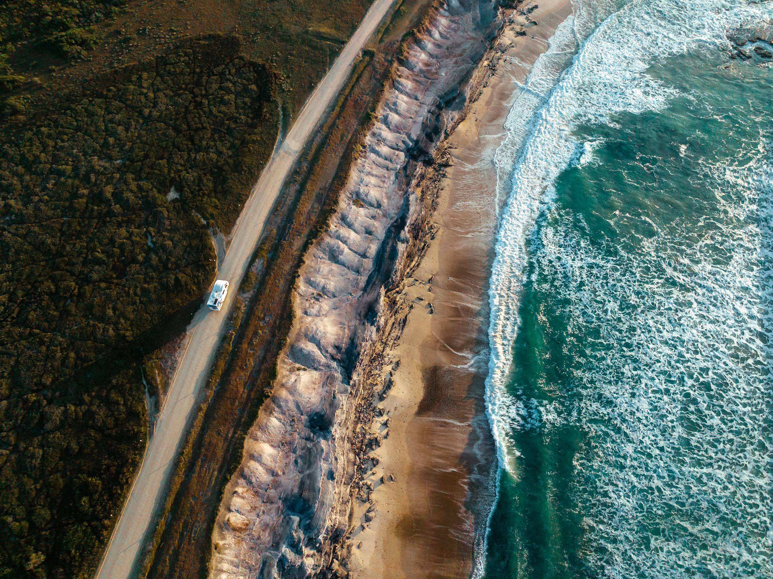 Drone shot overhead of Star RV Polaris 6 motorhome hire driving on oceanic road