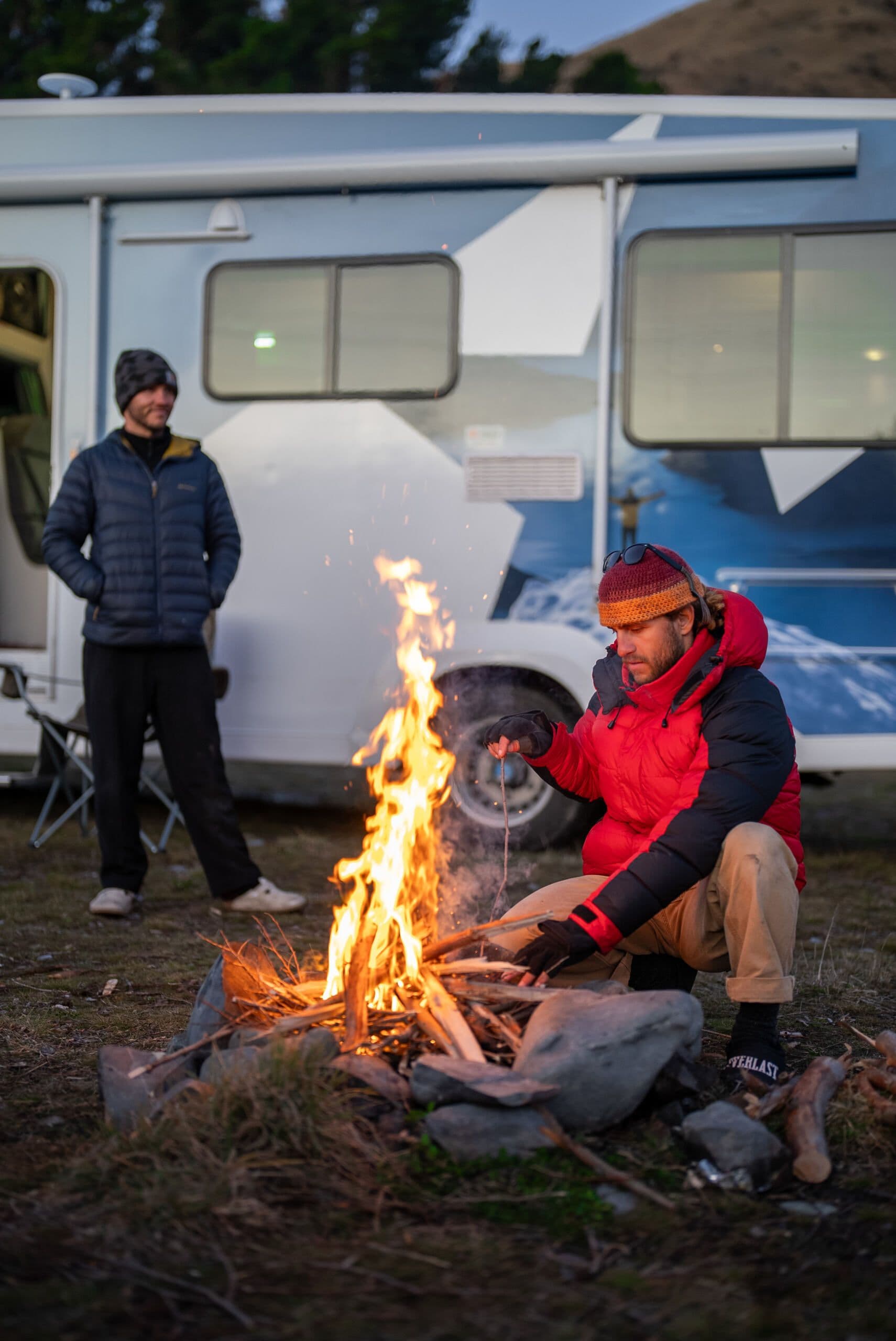 Man sitting at campfire in winter clothing next to a Star RV motorhome