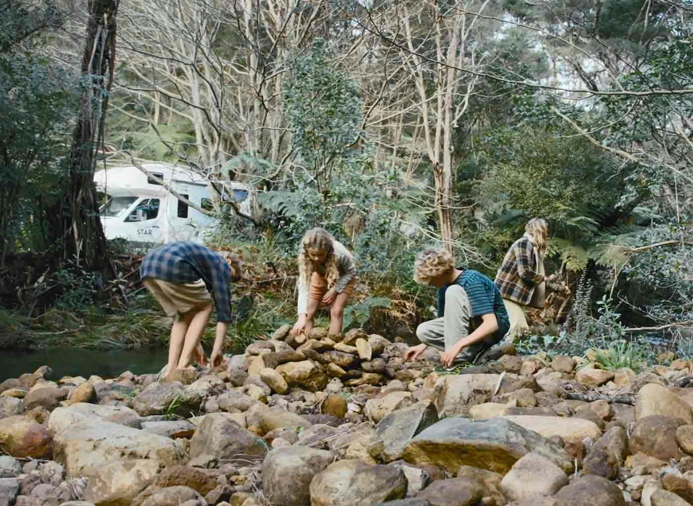 Children collecting stones by stream
