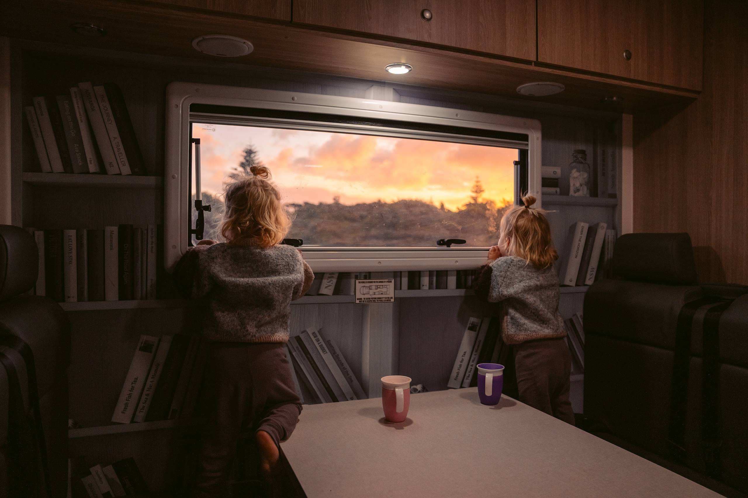 Two Twin girls sitting in Polaris 6 motorhome looking out the window